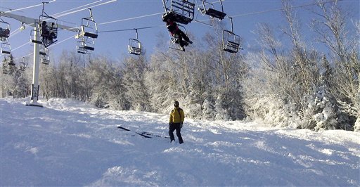 A skier tries to climb down from a stalled ski lift chair Tuesday.