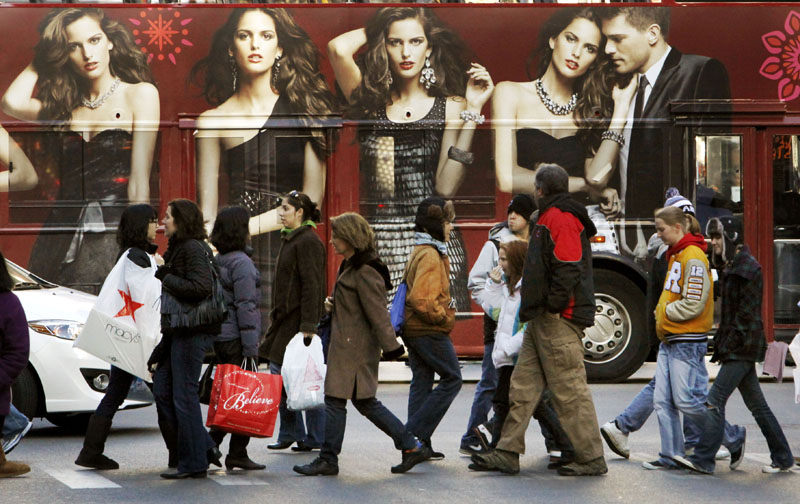 Shoppers walk in front of a tour bus with an Express clothing store ad on the side recently in Chicago.