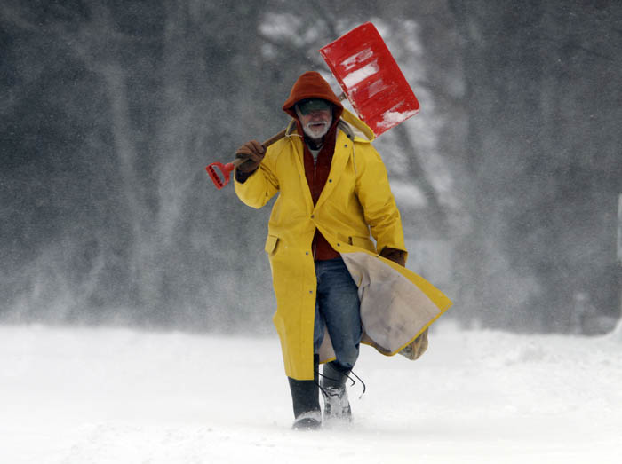 Snow swirls around Leo Picone, of Brunswick, Maine, as he makes his way along a road in Brunswick to shovel out customers.