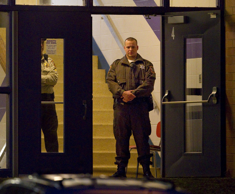 Law enforcement officials stand guard in the doorway of Marinette High School Tuesday morning. School officials say they plan to review safety guidelines at the school, which does not have metal detectors.