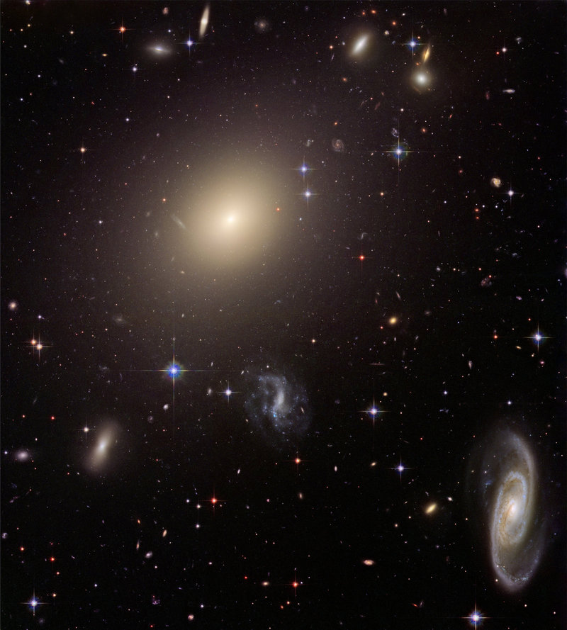 This photo provided by NASA, taken in 2006 by the Hubble Space Telescope, shows a cluster of diverse galaxies. A new study led by a Yale University astronomer looked at elliptical galaxies, such as the bright one in the top middle, and found they have far more stars than initially thought.