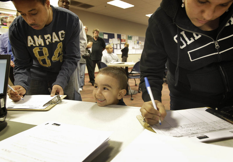 Diego Valdez, 3, waits for his mom, Veronica Majia, right, to sign in at a job fair in Phoenix, Ariz. More Americans applied for unemployment benefits last week, but the broader trend in layoffs points to a slowly healing jobs market.