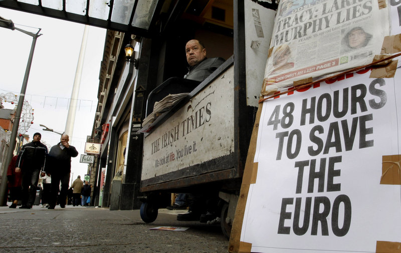A man sells newspapers that reflect Europe’s economic angst in Dublin, Ireland, last month. The debt crisis has forced eurozone governments to rewrite some of the currency union’s most fundamental rules.
