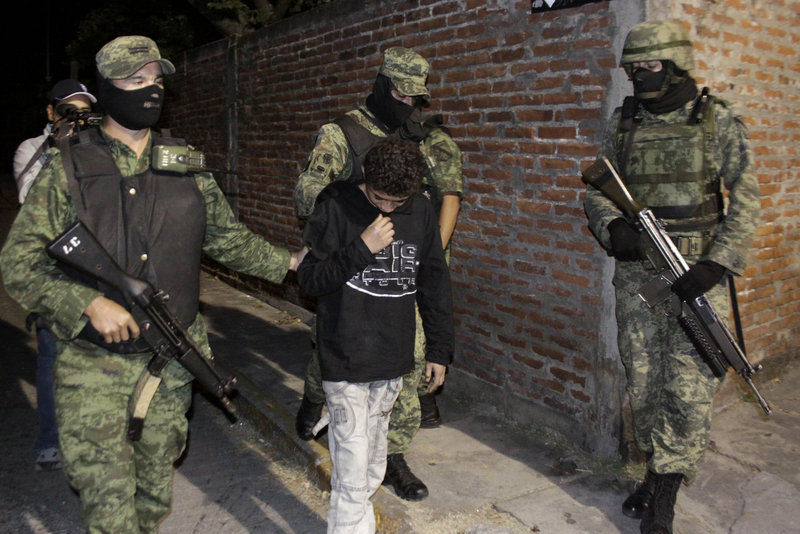 Mexican army soldiers on Friday escort a 14-year-old suspected of working as a killer for a drug cartel in the city of Cuernavaca, Mexico. “El Ponchis’’ was captured Thursday trying to flee to the U.S. with his 19-year-old sister.