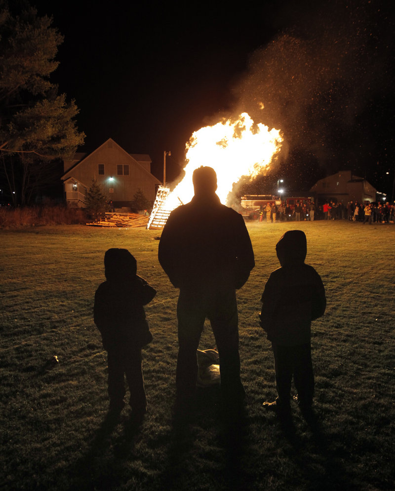 Sean Jenks of Kennebunk watches a bonfire with his sons Colby, 8, left, and Cian, 6, behind the Washington Hose Company in Kennebunk on Friday during Christmas Prelude.