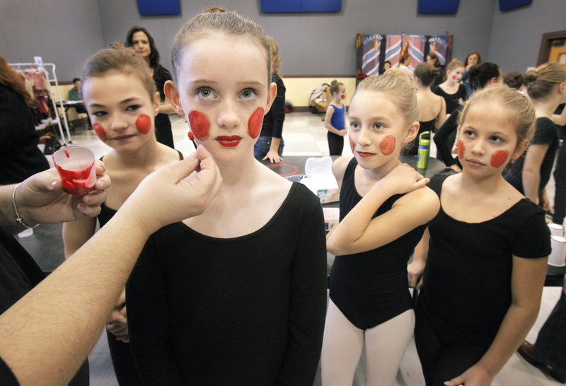 Julia Bisson, left, Erin Bruce and Dorrie Pinchbeck wait and watch as Jill Cass has her toy soldier makeup applied Saturday. The young performers are readied backstage by parents and volunteers in an assembly line-like process.