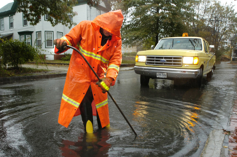 A city worker unclogs a Beacon Street catch basin after a heavy rain in 2005. Officials think “storage conduits” will help.
