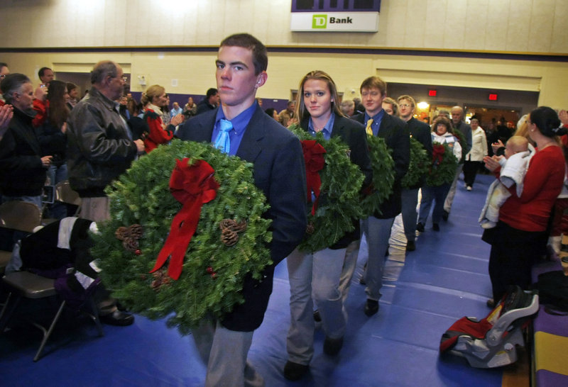Lars Murphy and other members of the Cheverus High School swim team lead the procession of wreaths into the Cheverus gymnasium as Wreaths Across America made a stop at the school for a special ceremony Sunday.