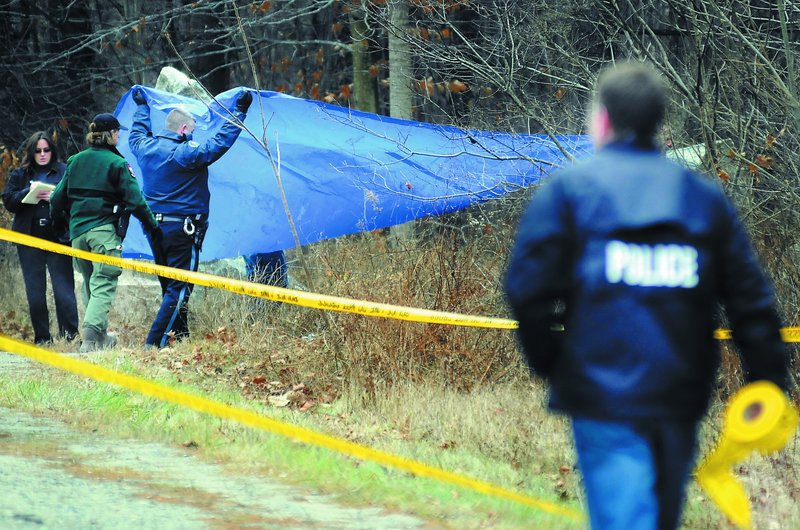 Andy Molloy/Kennebec Journal Police cover a body discovered Sunday by game wardens off Winthrop Street in Hallowell. Wardens searching with dogs located the body about noon near a granite quarry.u FEFF