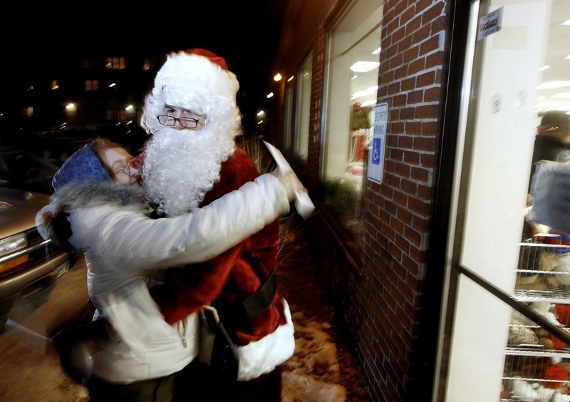 Santa Claus gets a hug from Aurea Parker last year after Parker received $100 at the Goodwill store on Forest Avenue in Portland. The anonymous businessman behind the giveaway is doubling the money and adding locations this year.