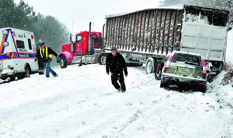 Monday’s storm caused this accident on southbound I-95 in Waterville. An occupant of the vehicle, right, trudges up the side of the road as emergency personnel attend to the scene. Three other vehicles slid off the road nearby.