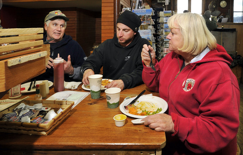 Linda Bean takes a break at her Port Clyde General Store to eat lunch with local residents Herb Beherrell, left, and Joshua Eldridge. Her conservative views influence her business strategy, with includes a deep distrust of Canada.