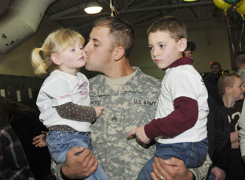Sgt. Alan Stanwood of Harrington gives his daughter Natalie, 2, a kiss as he holds his son Michael, 5, after returning with the Maine Army National Guard's Bravo Company, 3rd Battalion, 172nd Mountain Infantry in Bangor on Thursday.