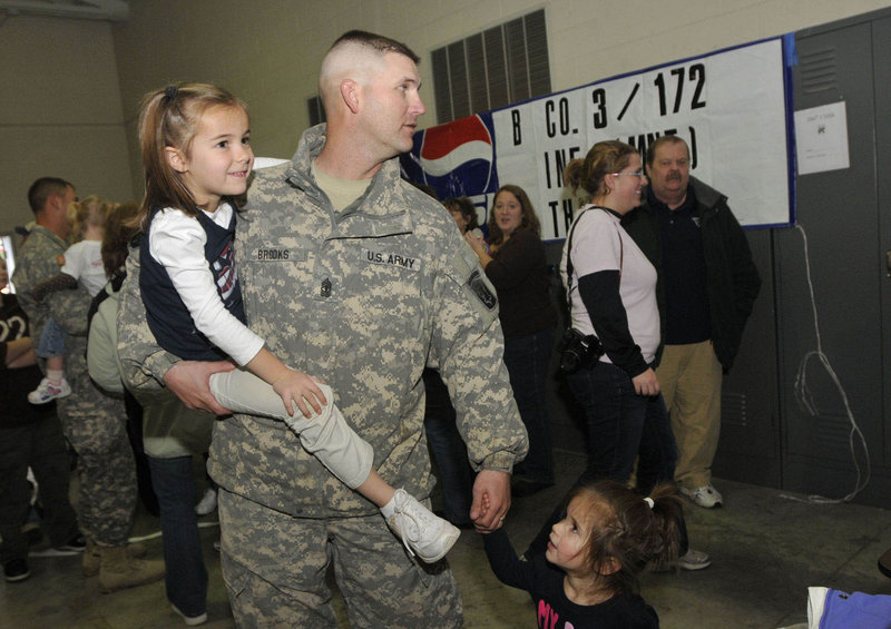 1st Sgt. John Brooks of Glenburn holds his daughter Elise, 5, and the hand of his daughter Audra, 2, after the return of Bravo Company, 3rd Battalion, 172nd Mountain Infantry in Bangor on Thursday. "I'm just ready to go home and be called Dad," Brooks said.
