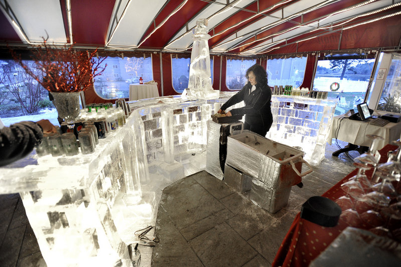 Bartender Teresa Gamache sets up her newly created ice bar at the Fire & Ice Bar benefit on Friday at The Nonantum Resort in Kennebunkport. Sculptor Ed Jarrett created the 18-foot-long bar from 16 blocks of ice. The two-night event continues from 4:30 to 9 tonight.