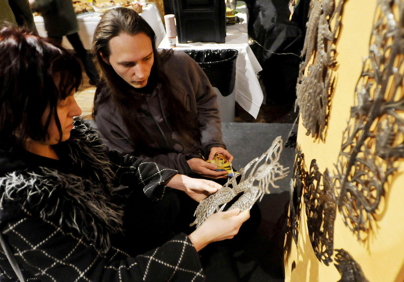 Erica Burkhart and Matiss Duhon, both of Portland, look over oil drum art pieces made in Haiti, during Konbit Sante s art sale on Saturday.