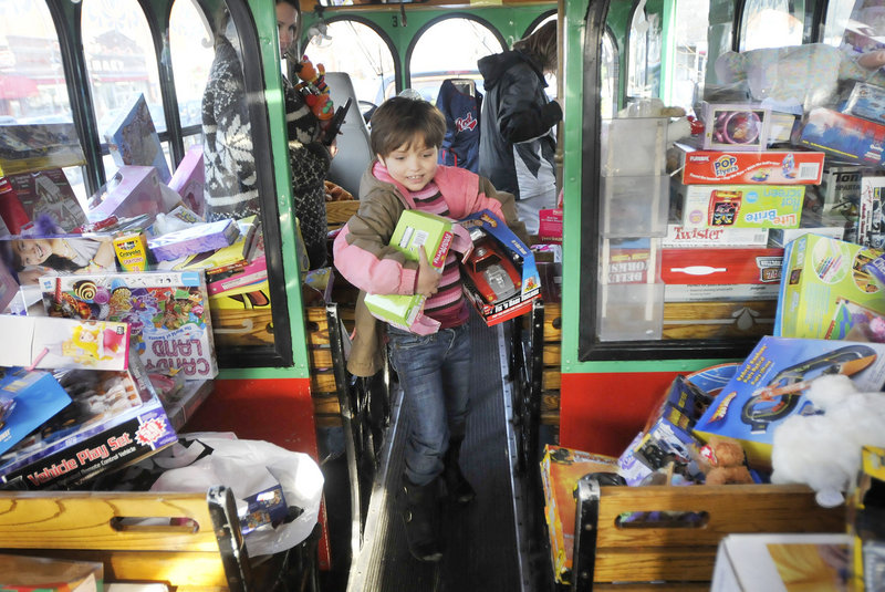 Mackenzie Rollins, 7, of Old Orchard Beach brings an armful of toys onto a Toys for Tots trolley as part of Saco Spirit’s Holiday Festival on Saturday. Mackenzie came with her mother, Kim Rollins, who volunteered with a group from Prime Toyota in Saco.