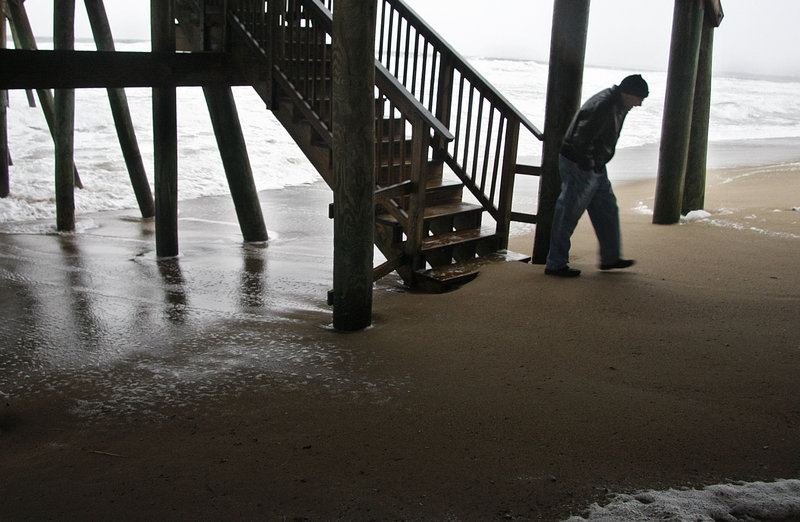 Bill White Jr. of Providence, R.I., walks near the pier in Old Orchard Beach on Sunday. Coastal flooding wasn’t expected because the astronomical tide cycle is ebbing.
