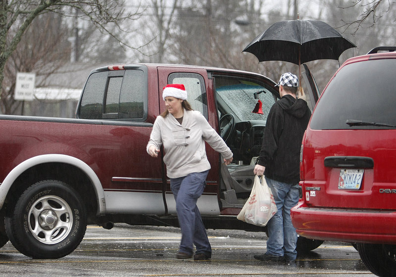 Michelle Minor dashes for cover after loading groceries with Derek Cote at Hannaford in Saco on Sunday. The two live in Old Orchard Beach. The rain is expected to continue today, but winds should die down.