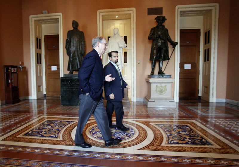 Republican Senate Minority Leader Mitch McConnell, R-Ky., left, walks back to his office with his Deputy Chief of Staff Rohit Kumar following two votes on tax cuts earlier this month.