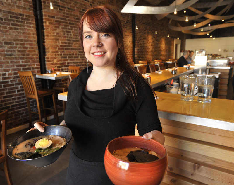 Gemma Hancock, a server at Pai Men Miyake, 188 State St. in Portland, displays a ramen dish and a bowl of spicy miso. The popular new Japanese restaurant is an attractive space, with exposed brick, handsome wood details and artfully arranged metalwork swooping from the ceiling.