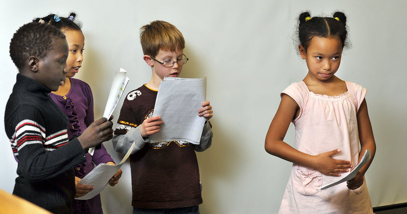 Kiah Alexis, 7, pats her tummy to show hunger as fellow cast members, from left, Mattew Oryem, 8, Kiah’s twin sister Kiana, and Jacob Bouchard, 8, all in second grade, read lines from “Stone Soup” during an exhibition at Riverton School.