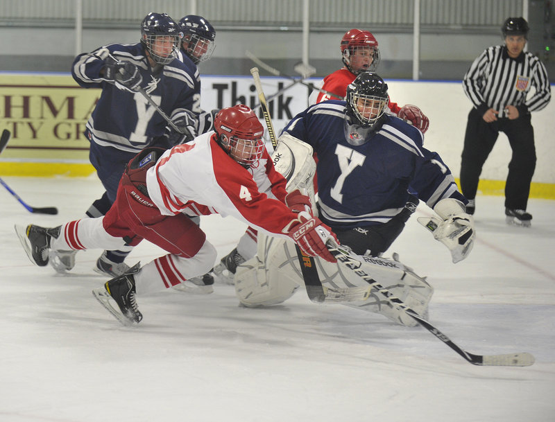 Robert Hannigan, who had two goals and three assists for South Portland, dives for the puck along with Yarmouth goalie Red DeSmith during their high school hockey game Thursday night at Portland Ice Arena. South Portland came away with a 7-0 victory.