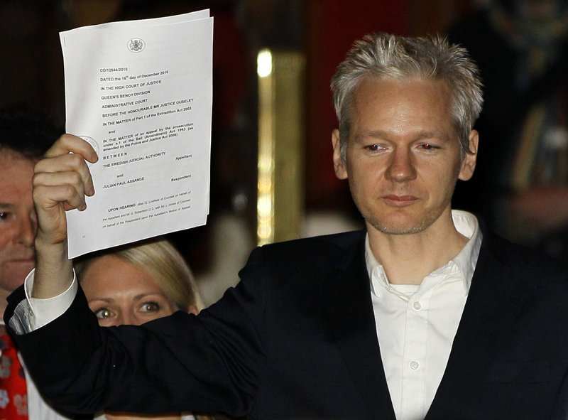 Julian Assange holds a court paper after being released on bail Thursday in London. Sweden is seeking his extradition for alleged sex crimes.