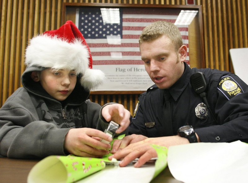 Anthony Troiano wraps a gift with Officer Mathew Dissell at the Portland Police Department. Officers view the program as a fun, stress-free way to spend their day off.