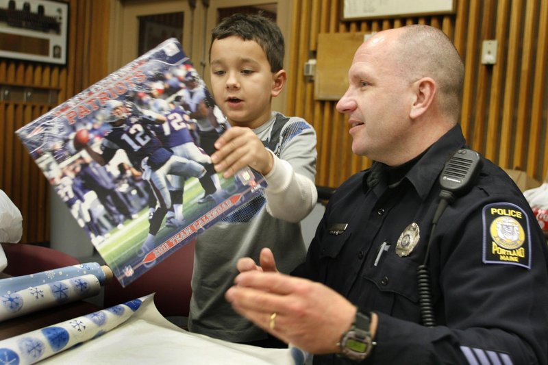 Seth Lehmus and Officer Les Smith wrap a calendar. Part of the department’s focus is to create positive interactions with youths that pay off in good relationships later.