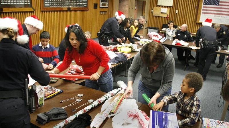 Officers and volunteers wrap gifts with kids during the Shop with a Cop program at the Portland Police Department on Friday. The program allowed local kids to shop at Target, wrap the gifts at the station and eat pizza.