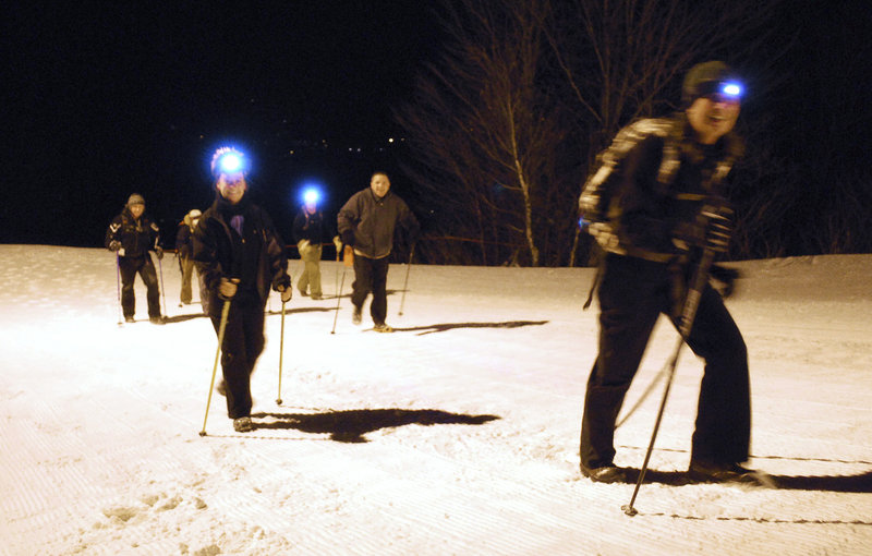 Susan Kilbride of Freeport, left, and Christine Clark of Portland, right, finish an hour-long full moon trek up Mt. Abram with other hikers on Dec. 18.