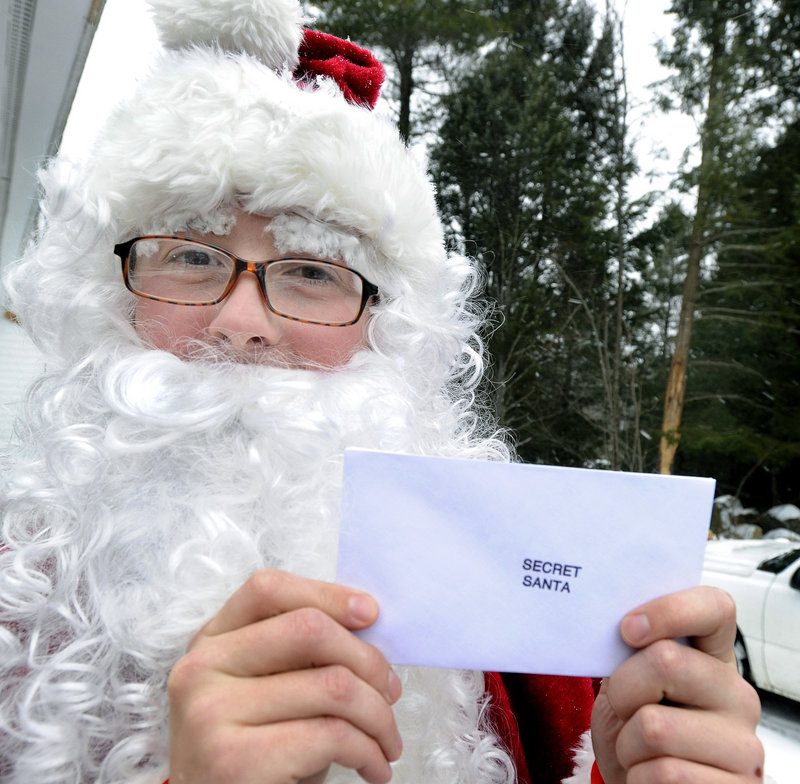 Secret Santa's helper holds one of many cash-filled envelopes he gave out Tuesday at a food pantry in Sebago, adding some extra joy to the season for the surprised recipients.