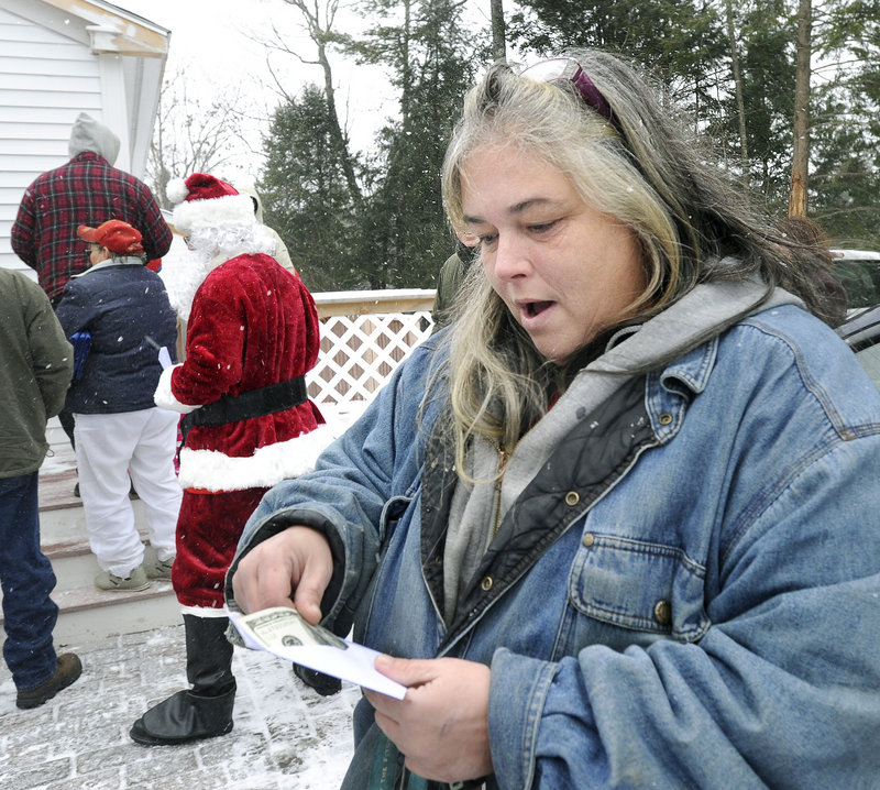 Patricia Ange is pleased by what she finds in an envelope given to her Tuesday when the Secret Santa paid a visit to the Warming Hut in Sebago to give away $100 bills. The benefactor plans to give away $20,000 this holiday season.