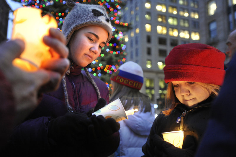 Maeve Porter-Holliday helps light a candle for Sophie Szatkowski, right, during the Homeless Persons Memorial Vigil.