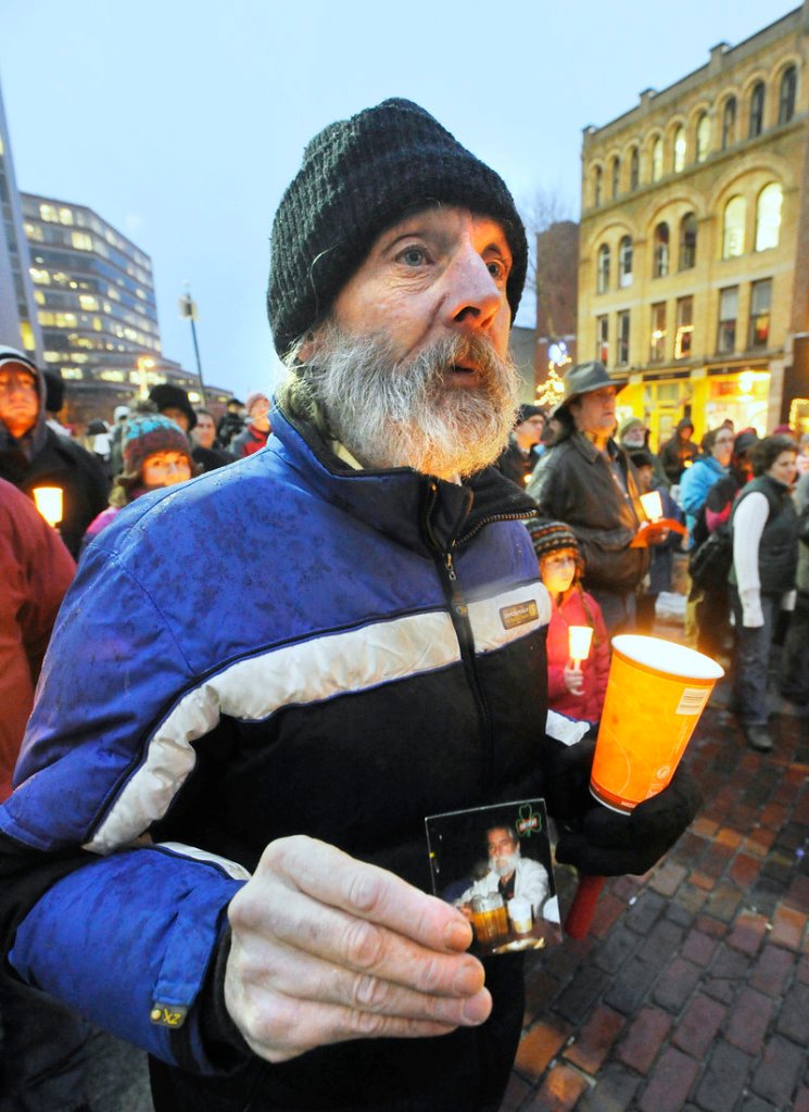 Al Libby, who is homeless, holds a photo of his friend Peter Garland at a vigil in Portland on Tuesday.