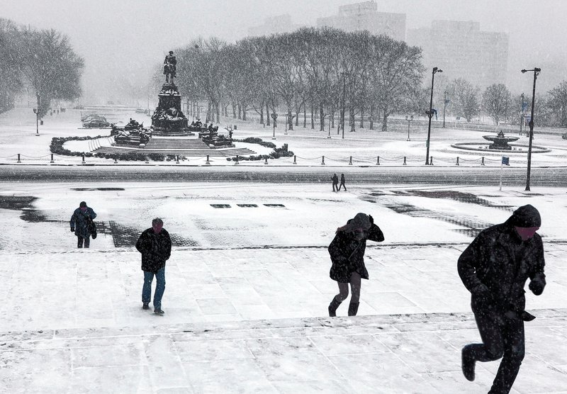 Tourists run up the Rocky Steps in front of the Philadelphia Museum of Art after Sunday's snowstorm in Philadelphia postponed the Vikings-Eagles game.