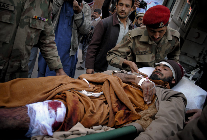 Pakistan army paramedics unload a man injured in a suicide bombing, at a hospital in Peshawar on Saturday. A female bomber killed 45 people outside a World Food Program food distribution center in Khar, triggering a districtwide suspension of the relief project.