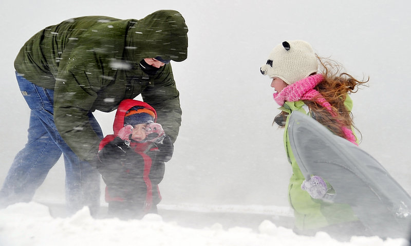 Josh Bankhead of Portland comforts his 3-year-old son, Moses, during a sudden squall of snow and wind on the Eastern Prom as his daughter, Adara, 10, hangs onto her sled blowing in the wind Monday. Cold temperatures and winds are expected to continue today.