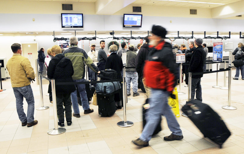 Travelers line up at US Airways at the Portland International Jetport. Under new regulations, flights that might have made an attempt to take off in bad weather in the past are now canceled.