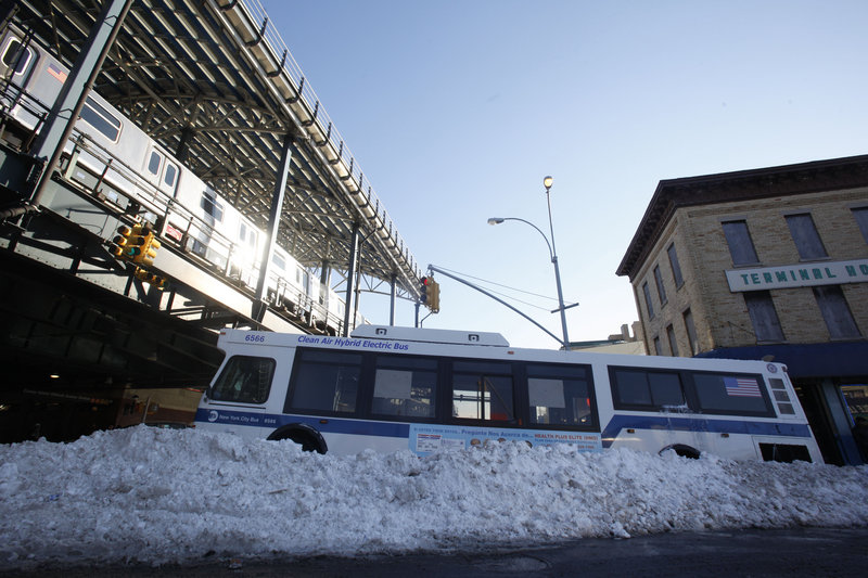 A city bus sits stranded in the street Tuesday amid snowbanks clogging a neighborhood in Brooklyn. On local highways, more than 1,000 abandoned vehicles had to be removed.