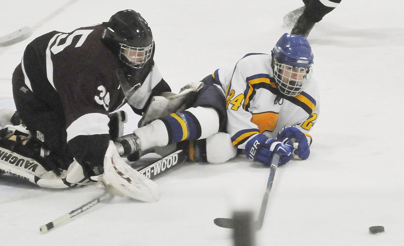 Mitch Tapley of Falmouth reaches for the puck Wednesday while sliding into Mike Amarone, the goalie for North Haven, Conn. The holiday tournament gives Maine teams the opportunity to test themselves against others.