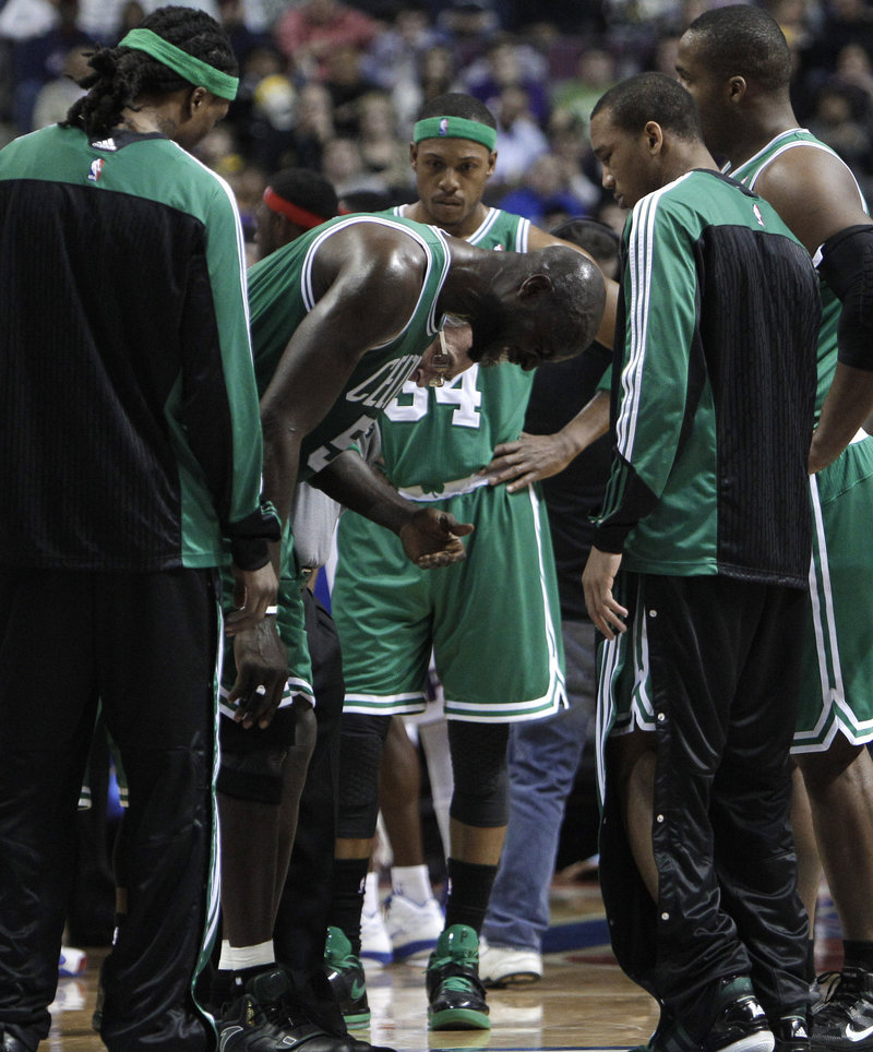 Kevin Garnett is surrounded by teammates while grimacing in pain Wednesday night in the first quarter of the Boston Celtics’ 104-92 loss to the Detroit Pistons.