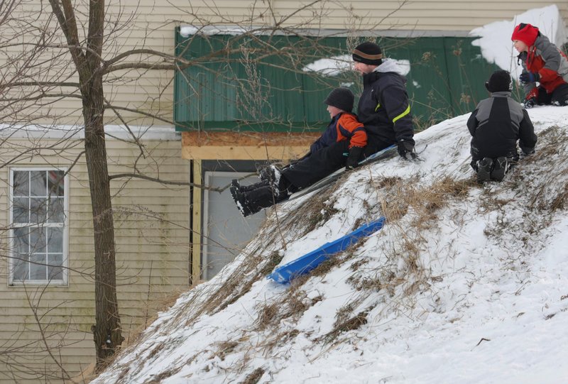 Chet Hanscom of Benton and his 8-year-old son Christian take off on a steep sledding run on a hill off Sherwin Street in Waterville on Thursday. The Hanscoms were enjoying the day on the local hill with family and friends.
