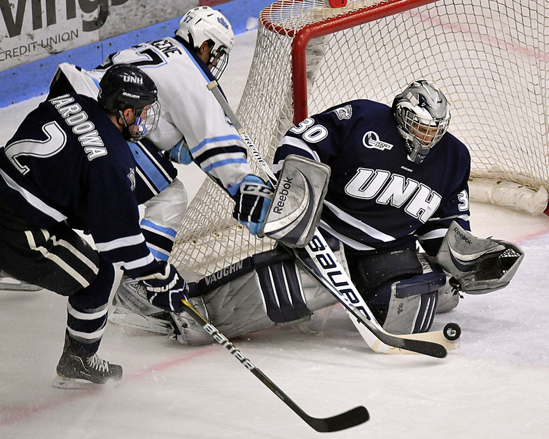 UMaine's Matt Mangene tries to slip the puck past UNH goalie Matt DiGirolamo as defenseman Connor Hardowa closes in. The Black Bears held a 3-1 lead entering the third period before the Wildcats rallied for a 4-3 win in OT.