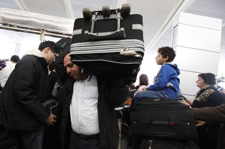 A man carries his luggage at the departure terminal of Cairo's international airport today, where thousands seek to flee the unrest in Egypt and countries around the world send in planes to fly their citizens out.