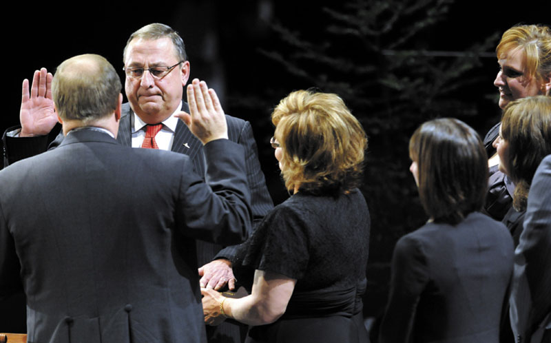 Gov.-elect Paul LePage takes the oath of office today from Senate President Kevin Raye, R-Perry, as wife Ann LePage holds the Bible and their children watch at the Augusta Civic Center.
