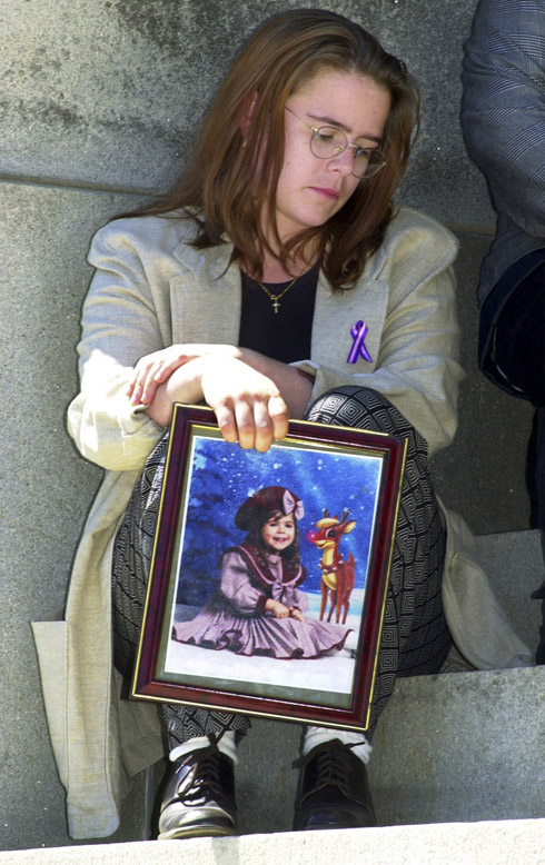 In this April 23, 2010 photo, Christy Baker sits outside the State House in Augusta following a news conference. She holds a photo of her daughter, Logan Marr, 5, who died on Jan. 31, 2001, while in foster care.