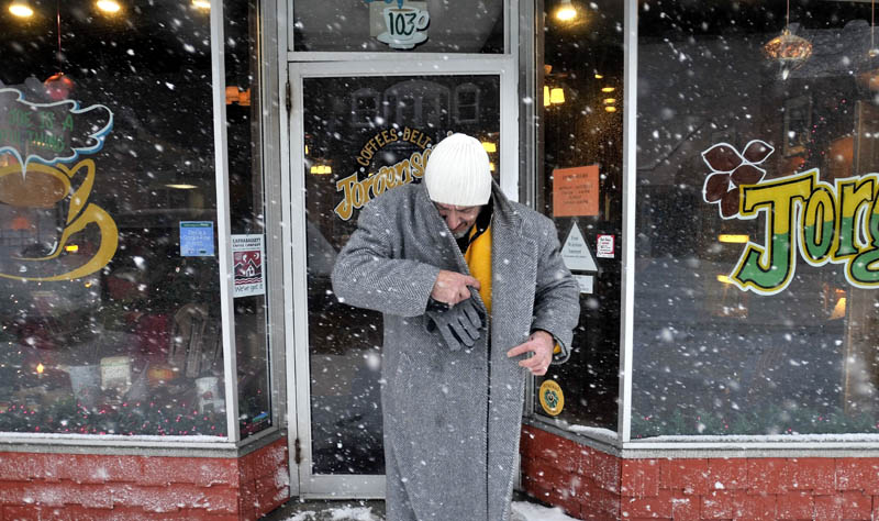 Staff photo by Michael G. Seamans Tony7 Karter budles up as he leaves the warm confines of Jorgensen's Cafe on Main Street in heavy snow Wednesday morning in Waterville. The storm moved further inland then previously forecasted.