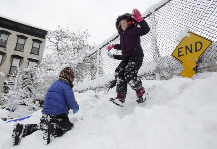 While her brother Seamus Lavelle, 4, left, climbs up, Sinead Lavelle, 5, jumps down a snow hill on their dead end street in Brooklyn, N.Y., today.